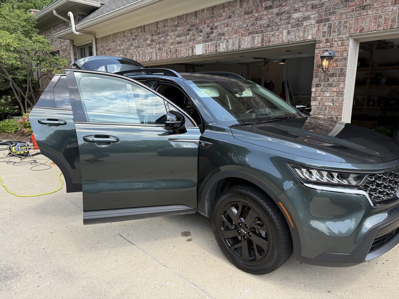 A detailed dark-green Kia Sorento with the door open, paint shining