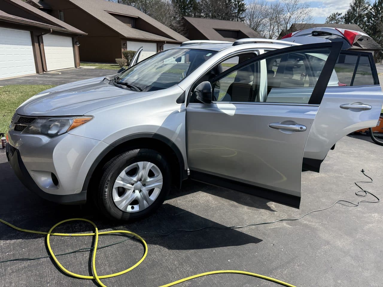 A silver Toyota RAV4 being detailed on-site with the doors open