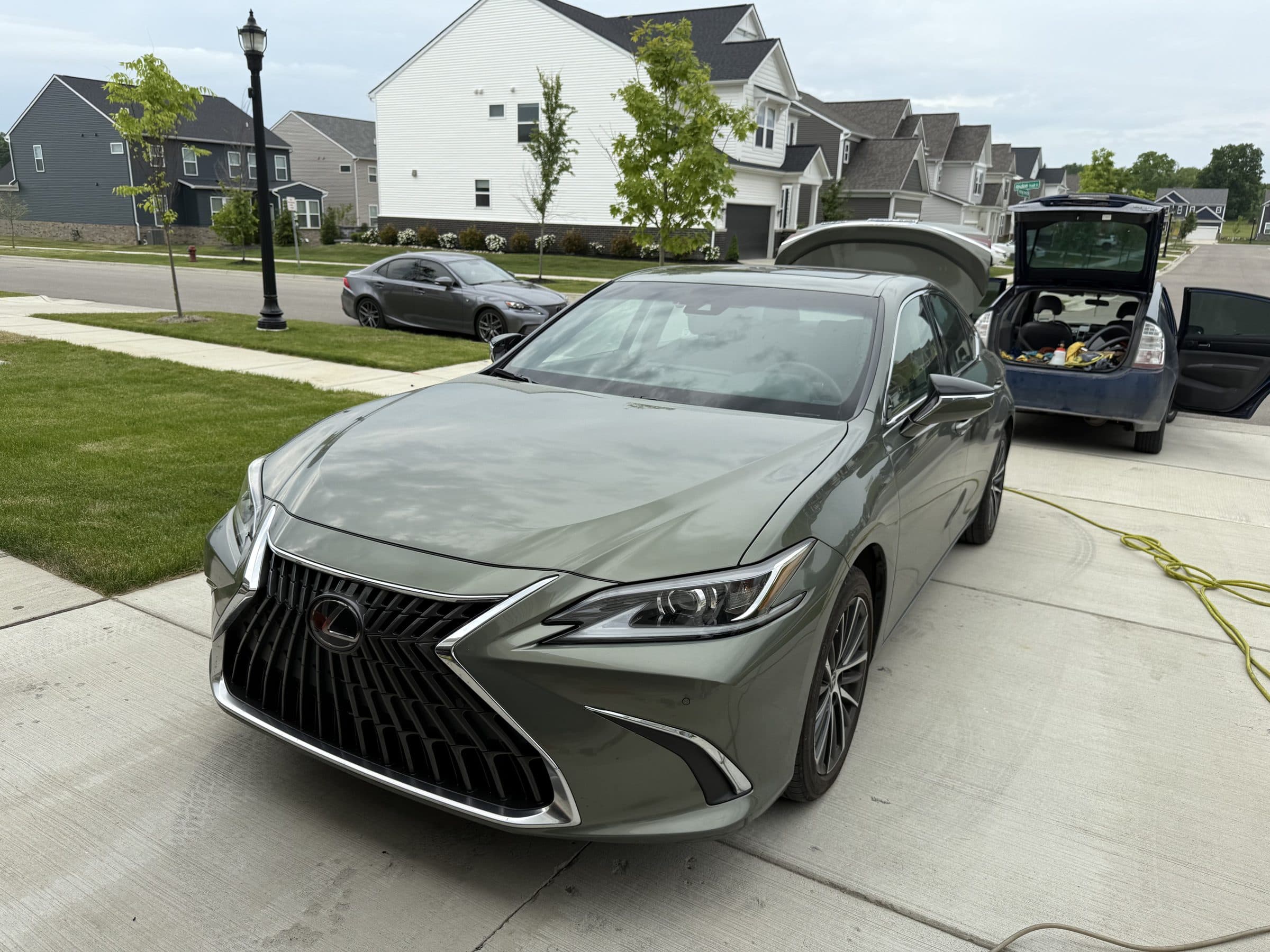 A freshly detailed sage-green Lexus ES sedan with a deep wet-look gloss, parked in a driveway
